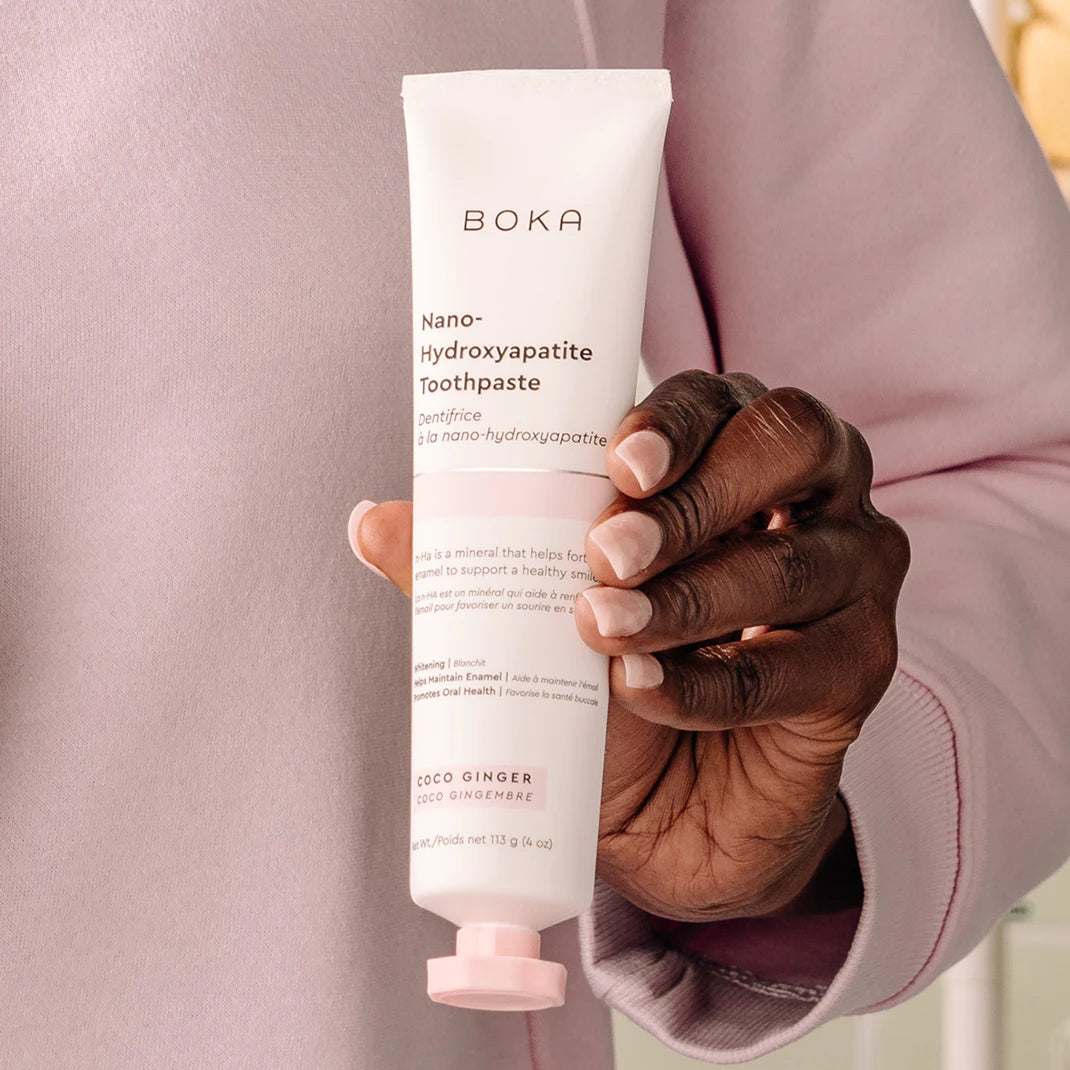 A person in a pink shirt holds a tube of Boka Nano-Hydroxyapatite Toothpaste.